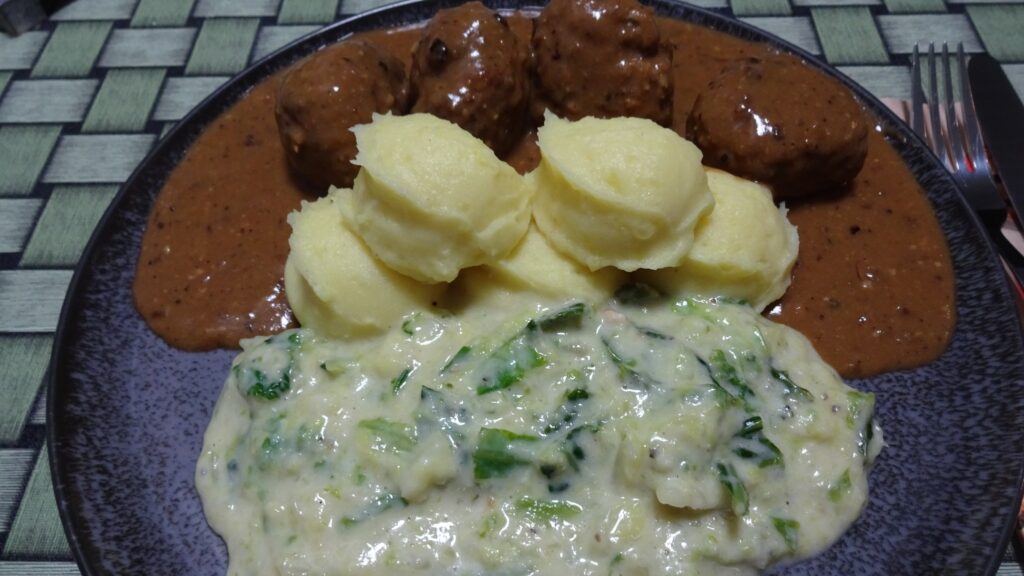 köttbullar mit brauner sauce, kartoffelbrei in kleinen bällen sowie rahmwirsing