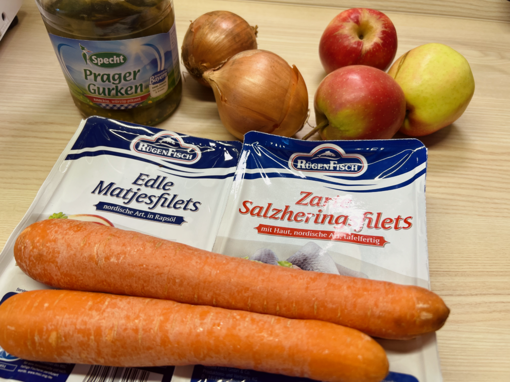 mise en place mit gelber rübe, abgepacktem fisch, zwiebeln, essiggurke und äpfeln