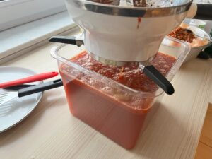 behälter mit passiermühle oben drauf fast voll mit tomatensauce